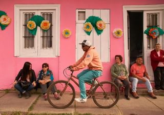 Man riding a bicycle set against colourful pink wall Maipo Valley Chile min Man riding a bicycle set against colourful pink wall Maipo Valley Chile min