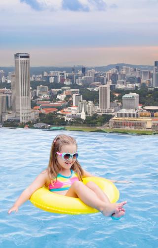 Child in pool overlooking Singapore skyline